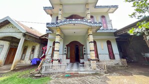 A multi-story building with a central entrance, flanked by two columns, and a tiled entrance area. - Hotel O Kost Berkah Near Kebun Teh Wonosari (Malang)