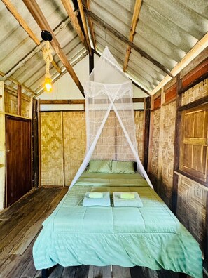 Una habitación con cama, mosquitera y paredes de madera.