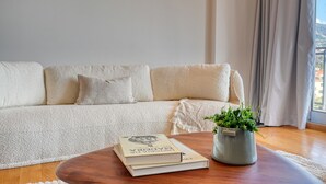 A living room with a beige sofa, a wooden coffee table, and a potted plant. - Funchal Atrium, a Home in Madeira (Funchal)