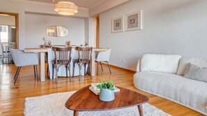 A modern living room with a sofa, coffee table, and dining area with chairs and a table. - Funchal Atrium, a Home in Madeira (Funchal)