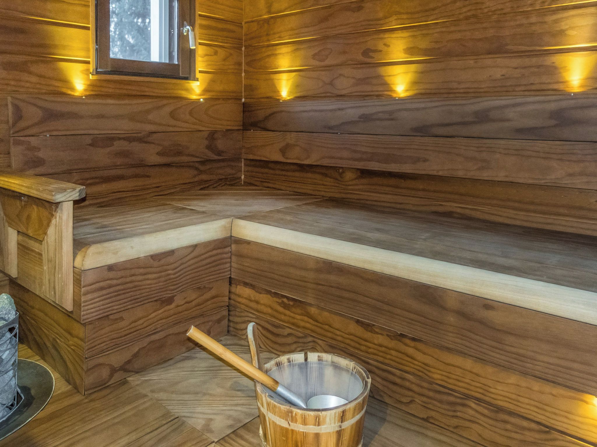 Una sauna de madera con bancos y un balde con una cuchara.