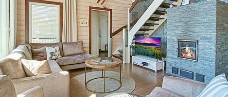Una sala de estar moderna con chimenea, una escalera y un ventanal grande.