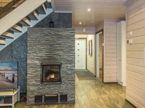 A modern interior with a stone fireplace, a staircase, and a hallway leading to a door. - Rantatähti by Interhome (Pudasjärvi)