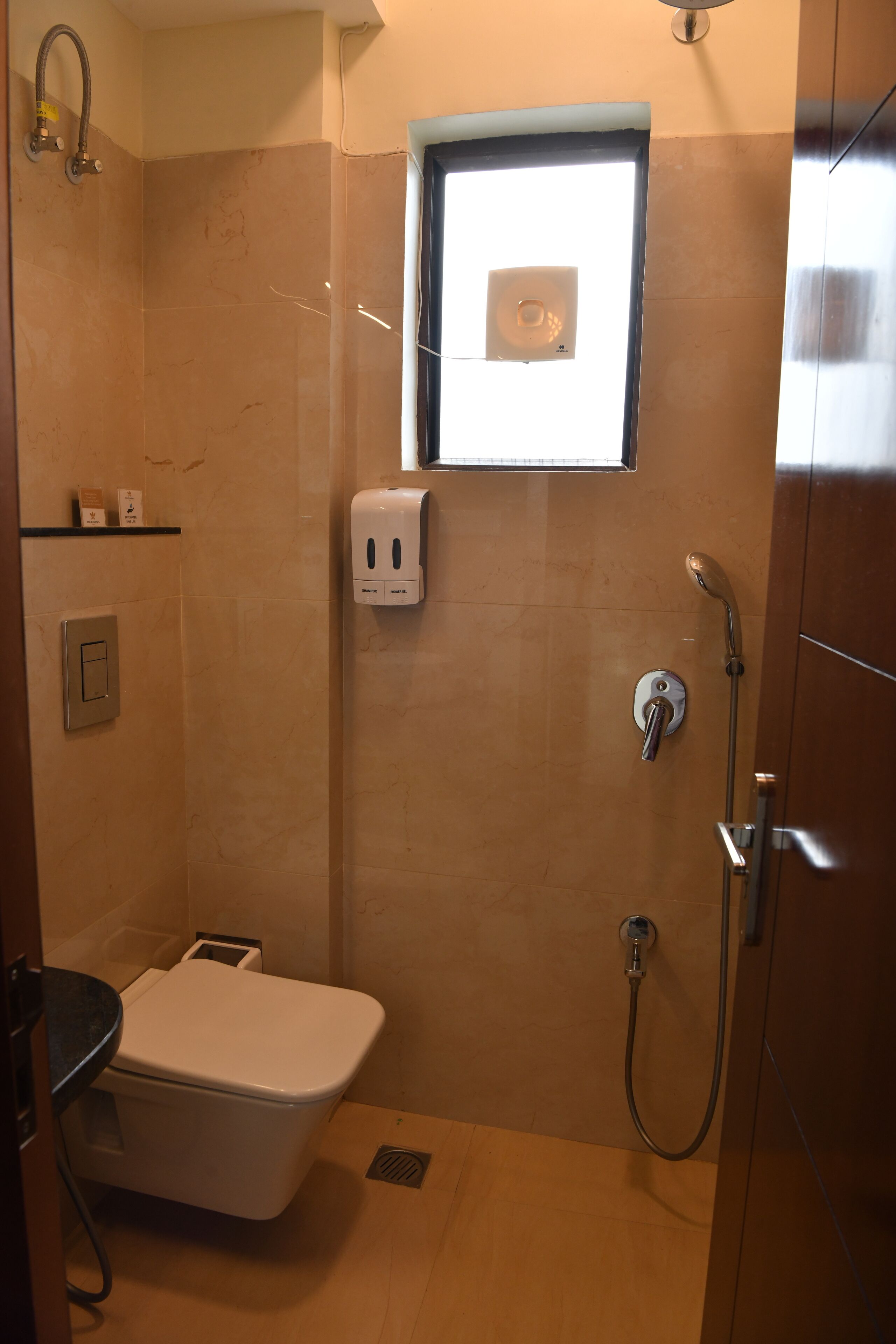Une salle de bain avec une douche, des toilettes et une fenêtre.