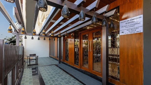 A covered outdoor area with a tiled floor, wooden doors, and hanging pendant lights. - Mertiya Residency (Jodhpur)