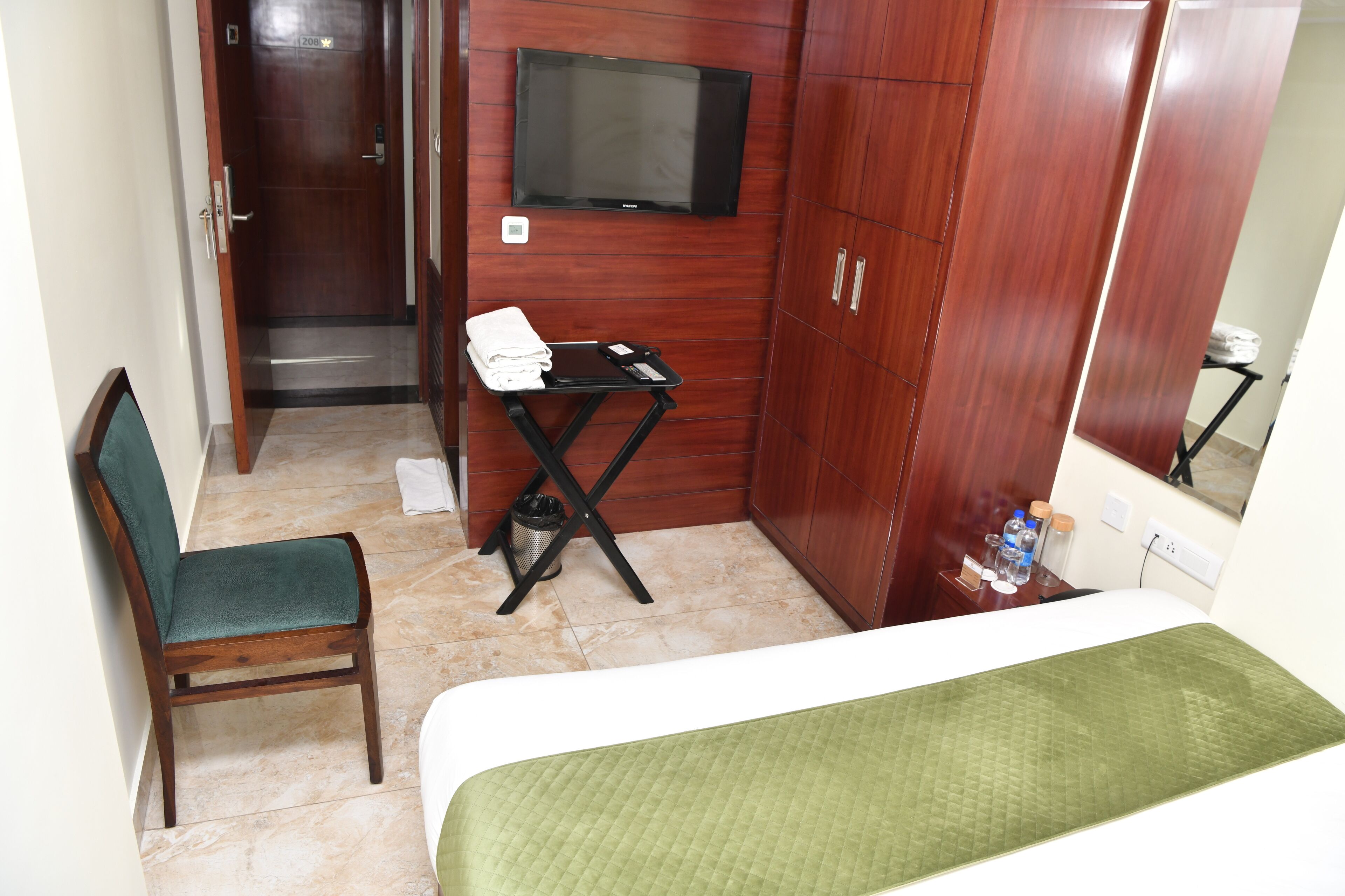 Een hotelkamer met een bed, een stoel, een klein tafeltje met een televisie en een spiegel.