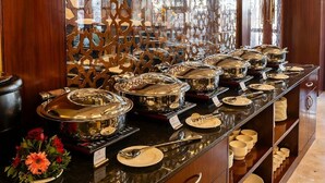 A buffet setup with multiple serving stations, each with a covered dish and serving utensils. - Mertiya Residency (Jodhpur)