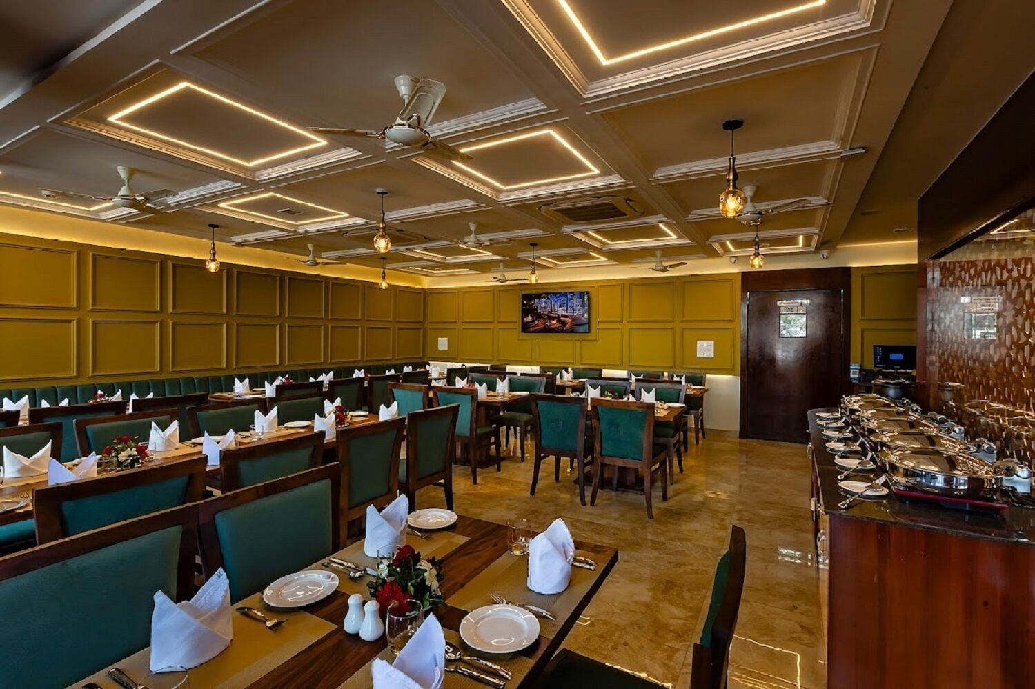 A restaurant with multiple dining tables, green upholstered booths, and ceiling fans.
