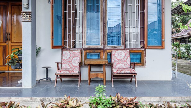 A traditional wooden building with a large window, two wooden chairs, and a small table. - Hotel O Delta Bnb Residence Syariah (Prabumulih)