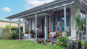 A house with a covered porch, potted plants, and outdoor furniture. - Hotel O Delta Bnb Residence Syariah (Prabumulih)