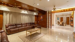 A spacious living room with a brown leather sofa, a coffee table, and a ceiling fan.
