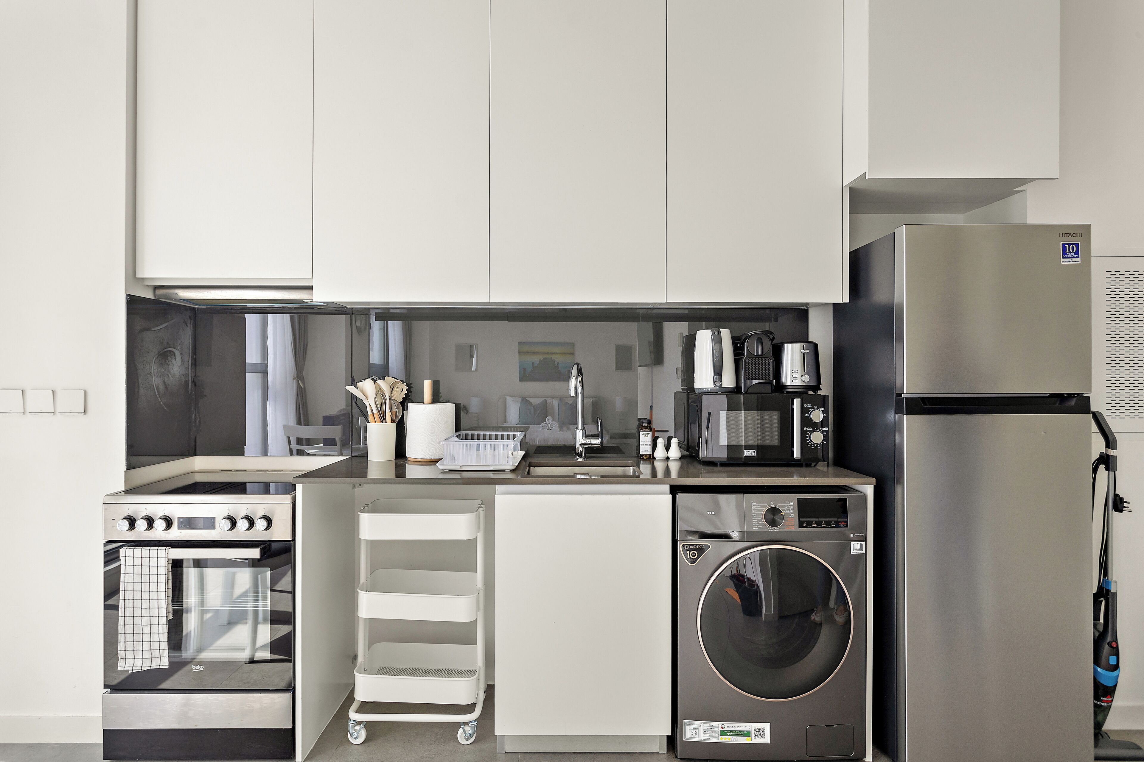 Cocina compacta con horno empotrado, microondas, refrigerador y lavadora.