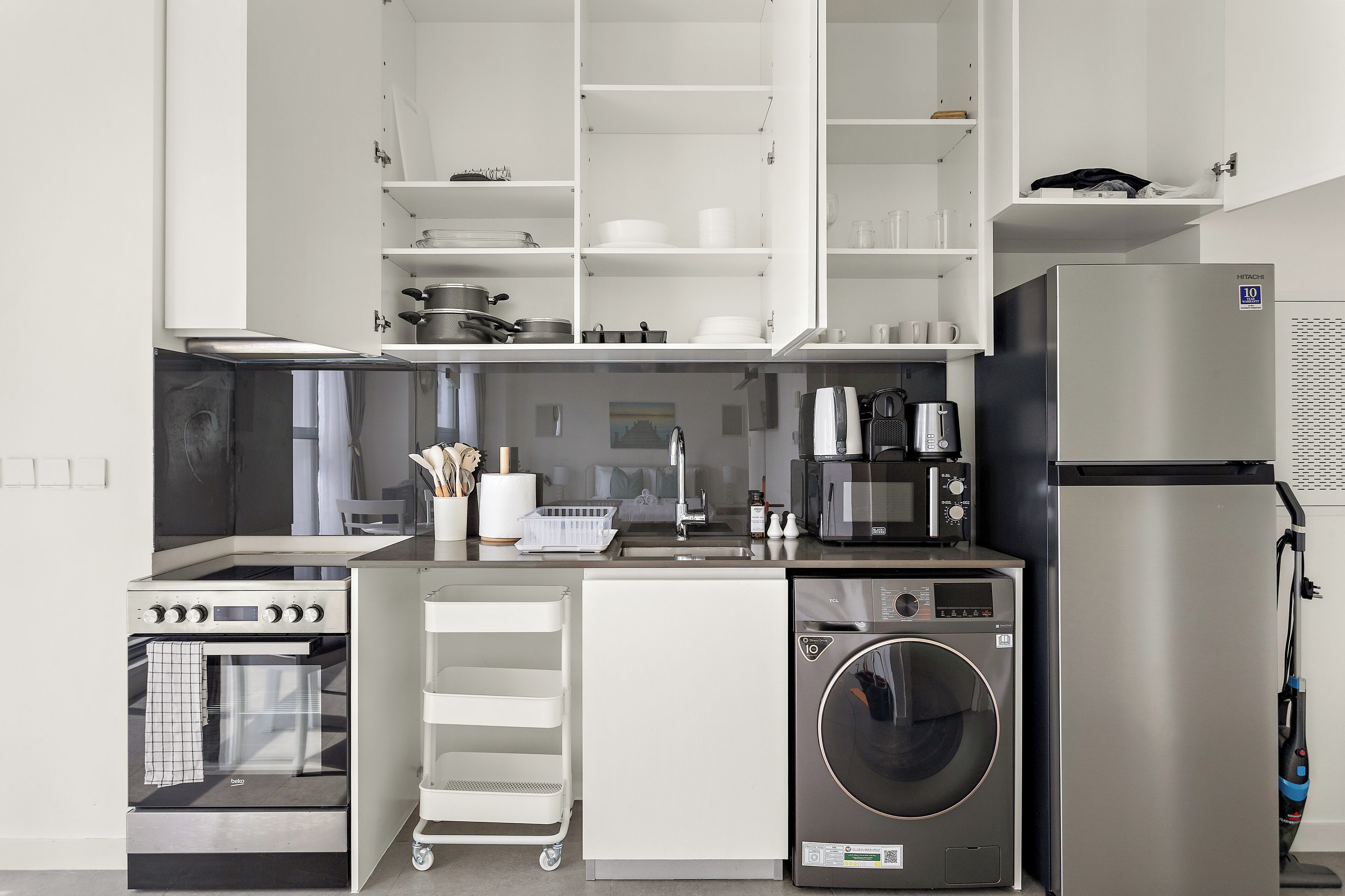 A compact kitchen with a built-in oven, microwave, coffee maker, and a washing machine.