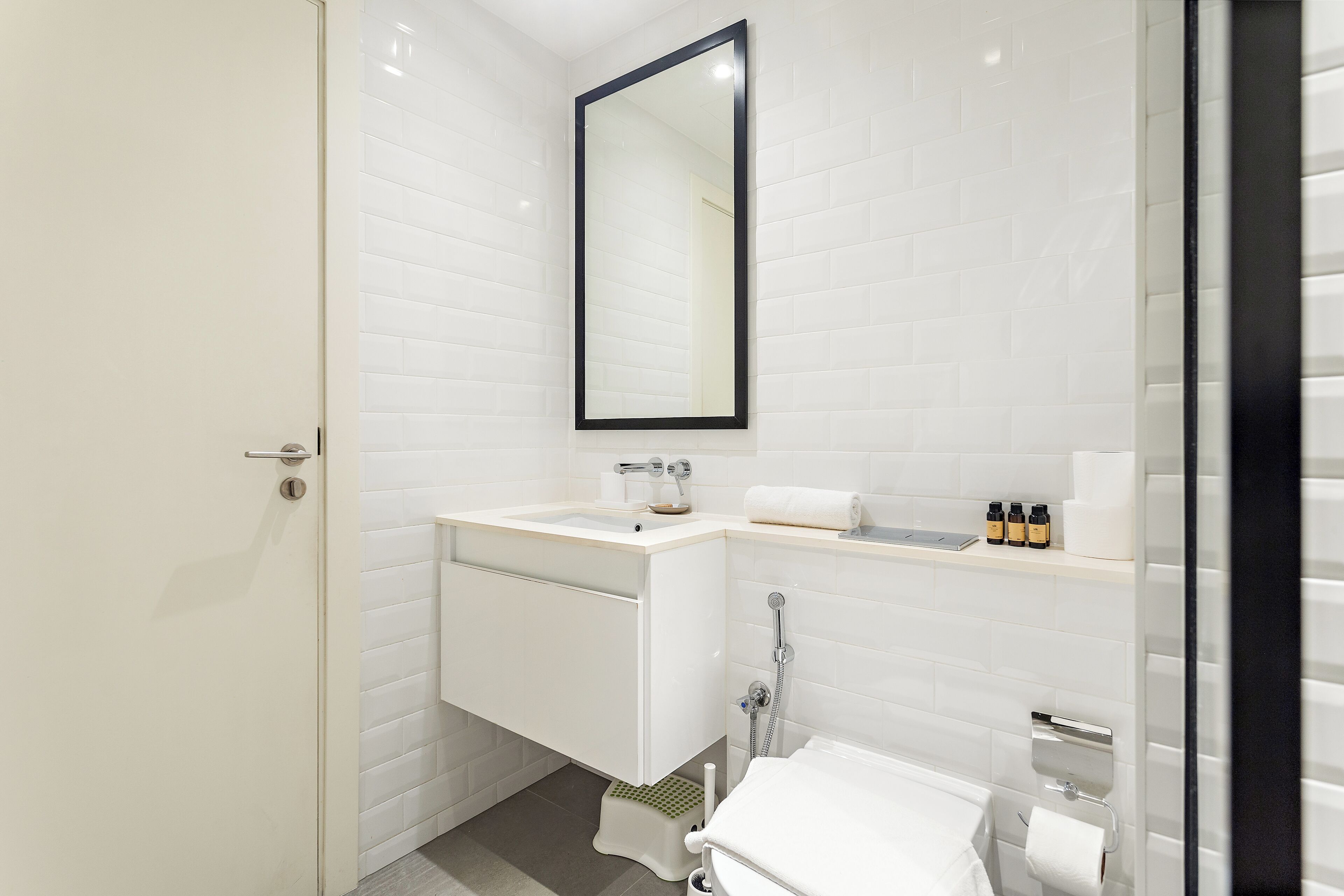 A modern bathroom with a white sink, mirror, and toilet.