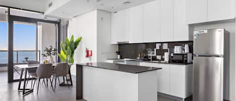 A modern kitchen with a central island, stainless steel appliances, and a view of the sea.