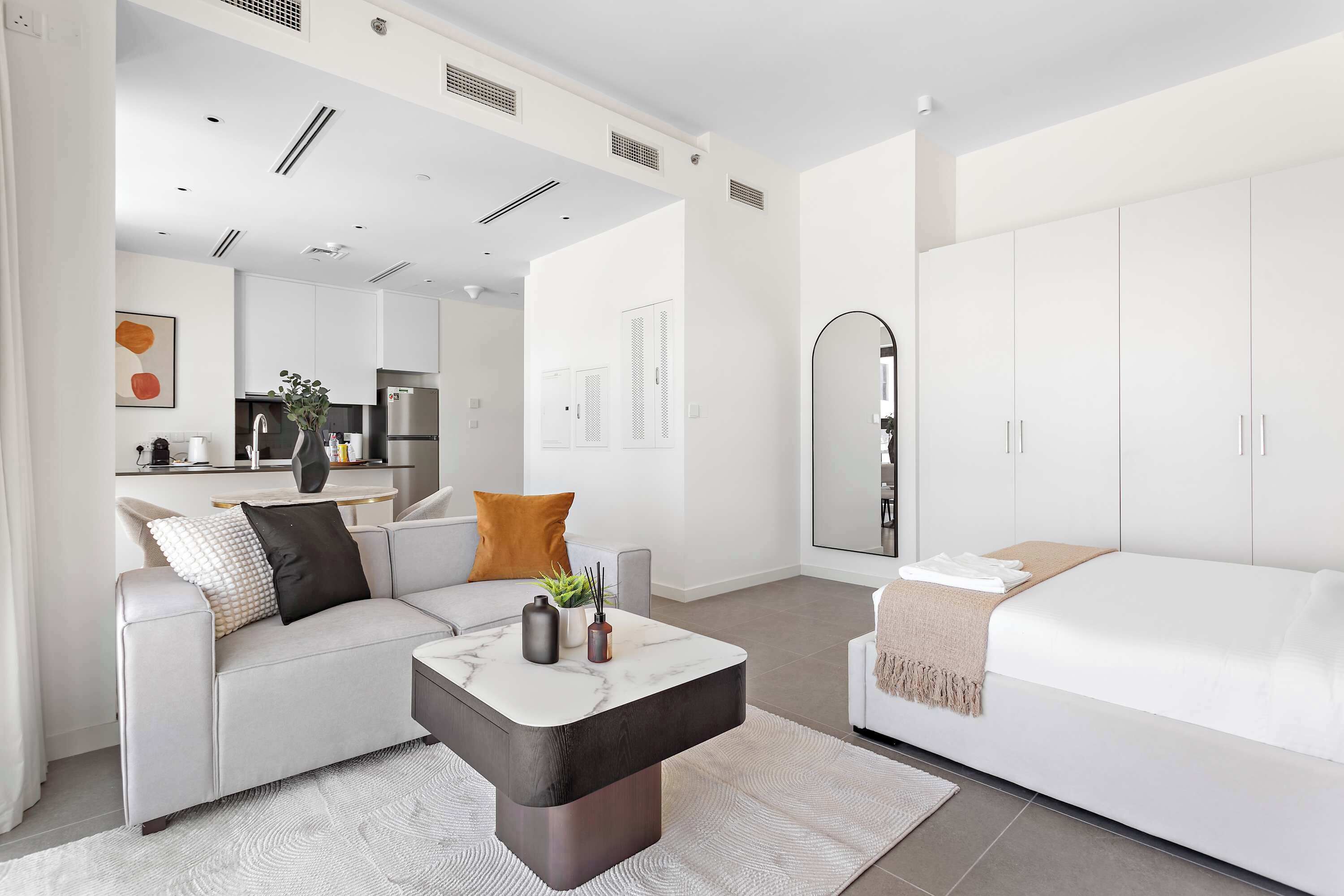 Een moderne, goed verlichte woonkamer met een bank, een salontafel en een bed.