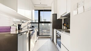 Eine moderne Küche mit Edelstahlgeräten, einem großen Fenster und Blick auf die Stadtlandschaft.