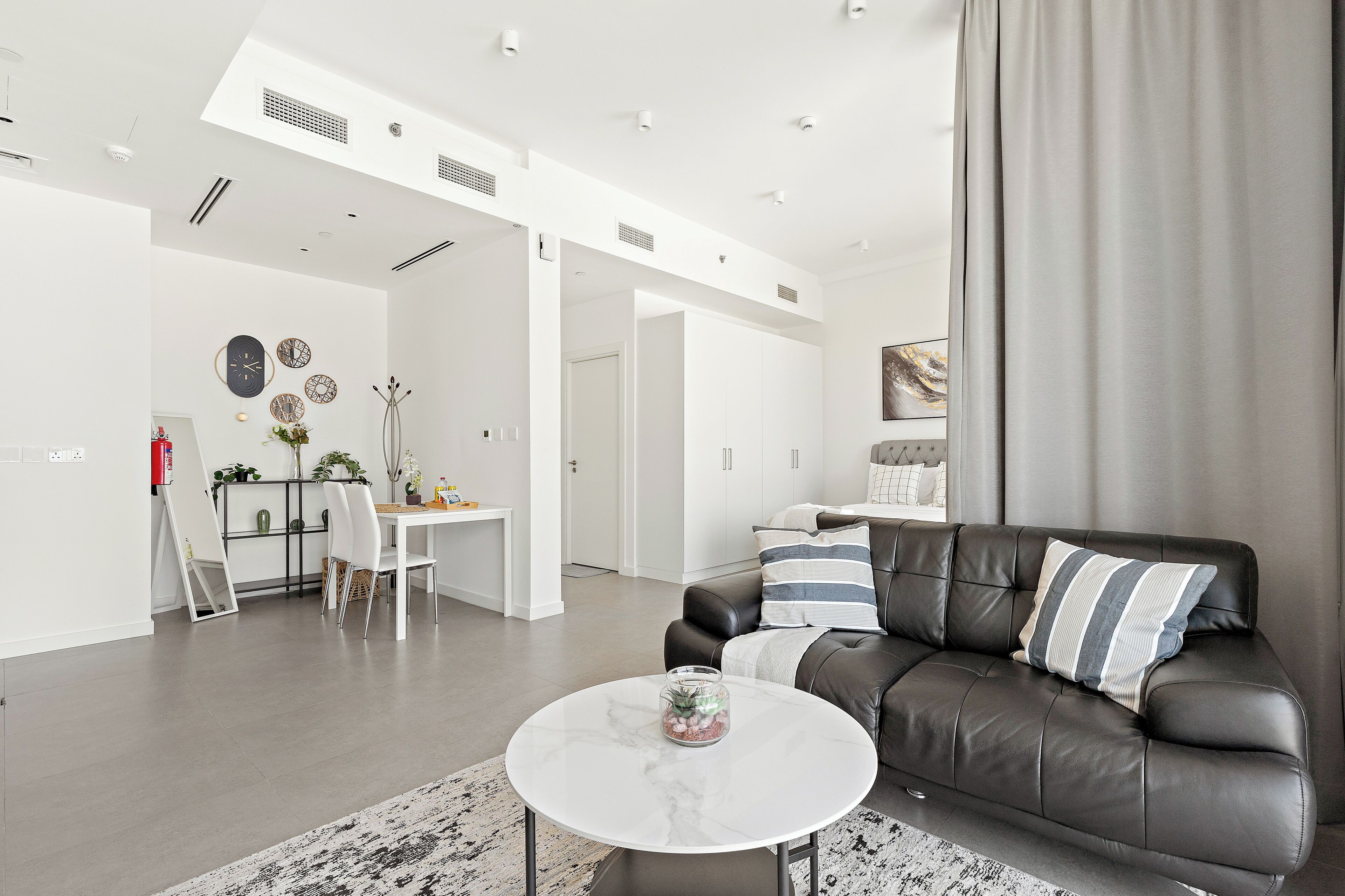 A modern living room with a leather sofa, a white coffee table, and a dining area with a white table and chairs.