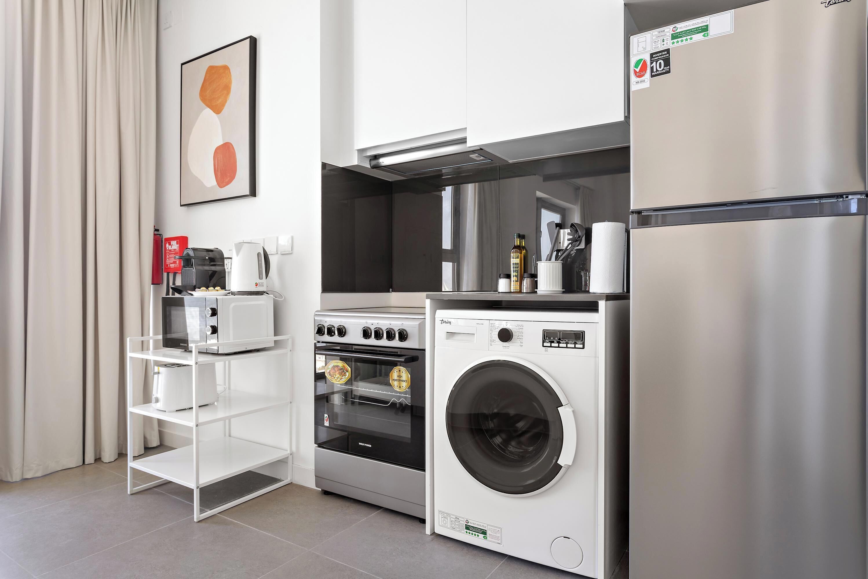 A compact kitchen with a built-in oven, microwave, and washing machine.