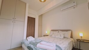 Ein Schlafzimmer mit einem Bett, zwei Nachttischlampen, einem Kleiderschrank und einer Klimaanlage.