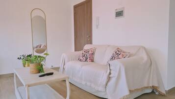 Un salon chaleureux avec un canapé, une petite table, une plante en pot et un miroir fixé au mur.