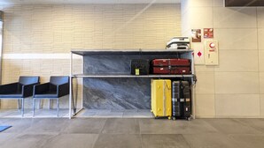 A reception area with a marble counter, black chairs, and luggage storage.