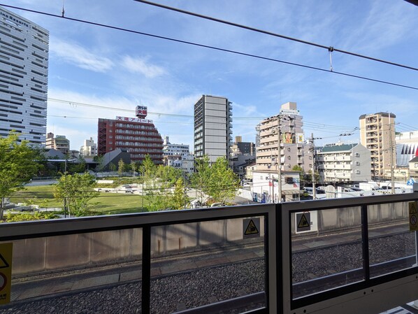 A cityscape with modern buildings, a train track, and a clear sky.