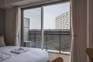A hotel room with a large bed, a view of a building through the window, and a balcony with a railing. - ESLEAD HOTEL Osaka Ebisu (Osaka)