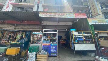 A street-side shop with a signboard advertising various services and products.