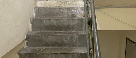 Unos escalones de hormigón con barandillas de metal que conducen a una puerta al final.