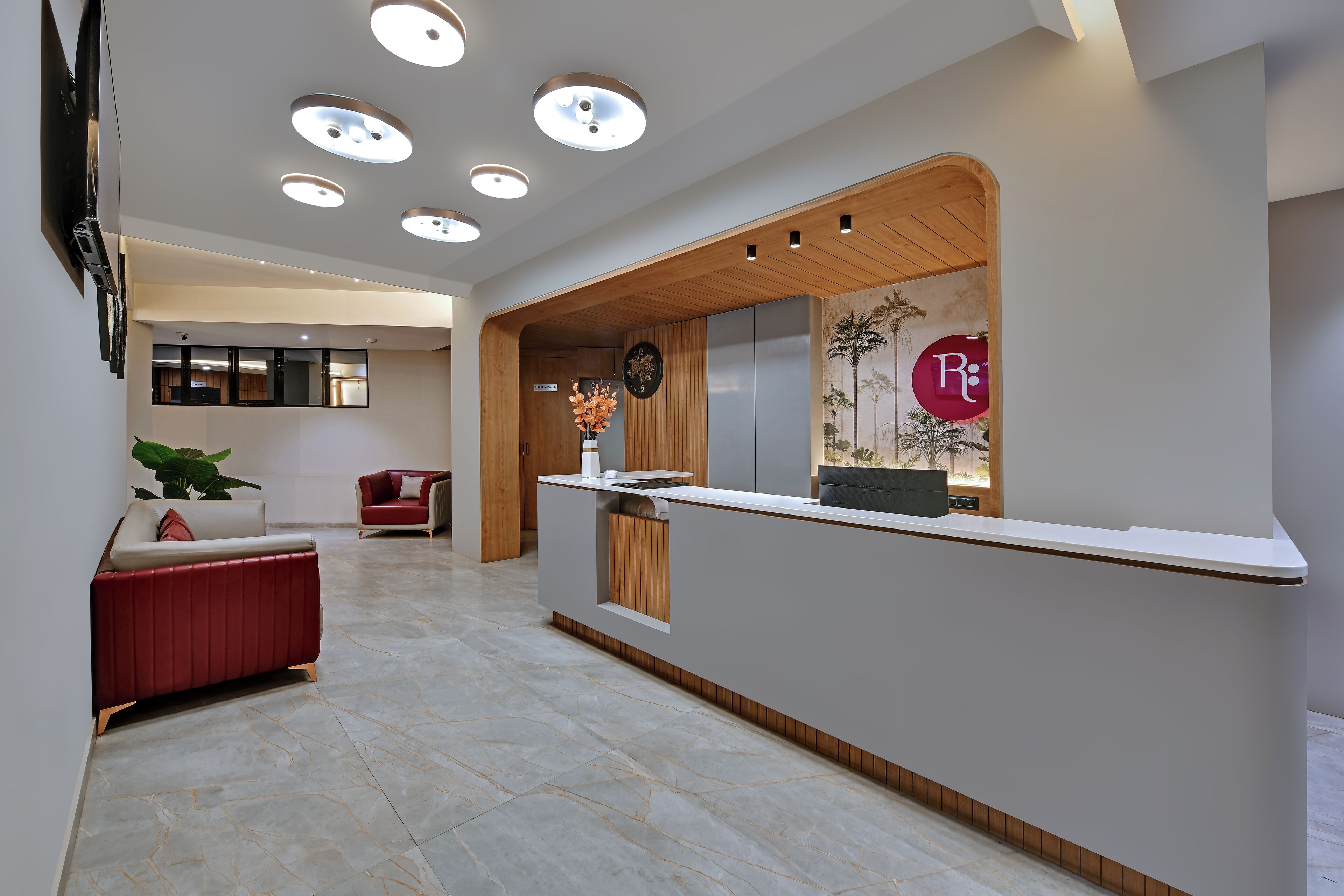 A modern reception area with a wooden reception desk, a red sofa, and a potted plant.