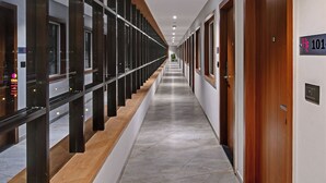 A long, narrow hallway with a wooden ceiling and a tiled floor. - Regenta Inn Motikhavdi Jamnagar  (Jamnagar)