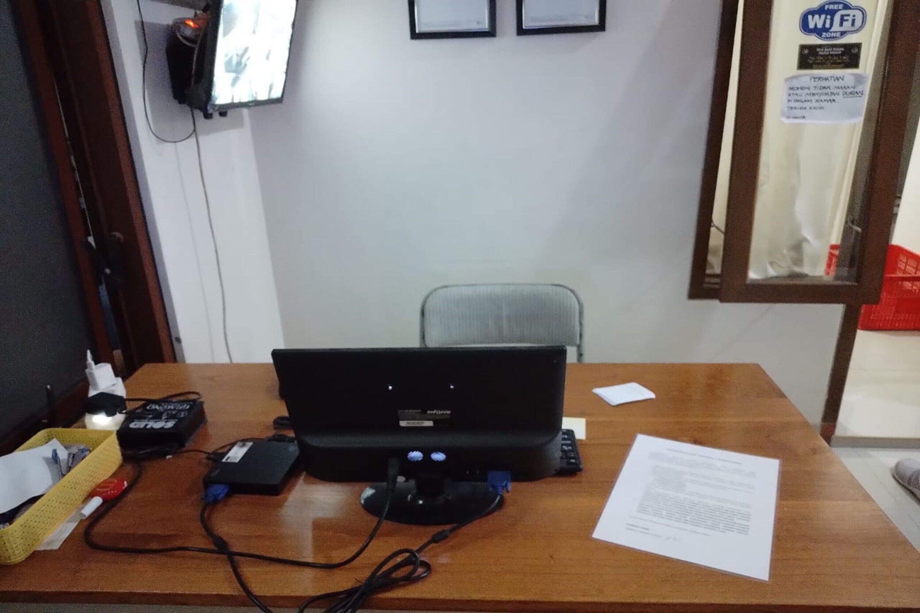 A wooden desk with a computer, a power strip, and a yellow basket.