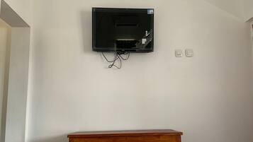 A television mounted on a plain wall with a wooden table in front.