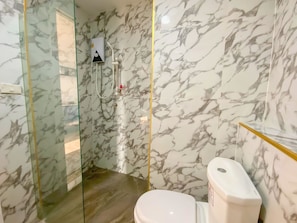 A bathroom with marble walls, a glass-enclosed shower, and a toilet.