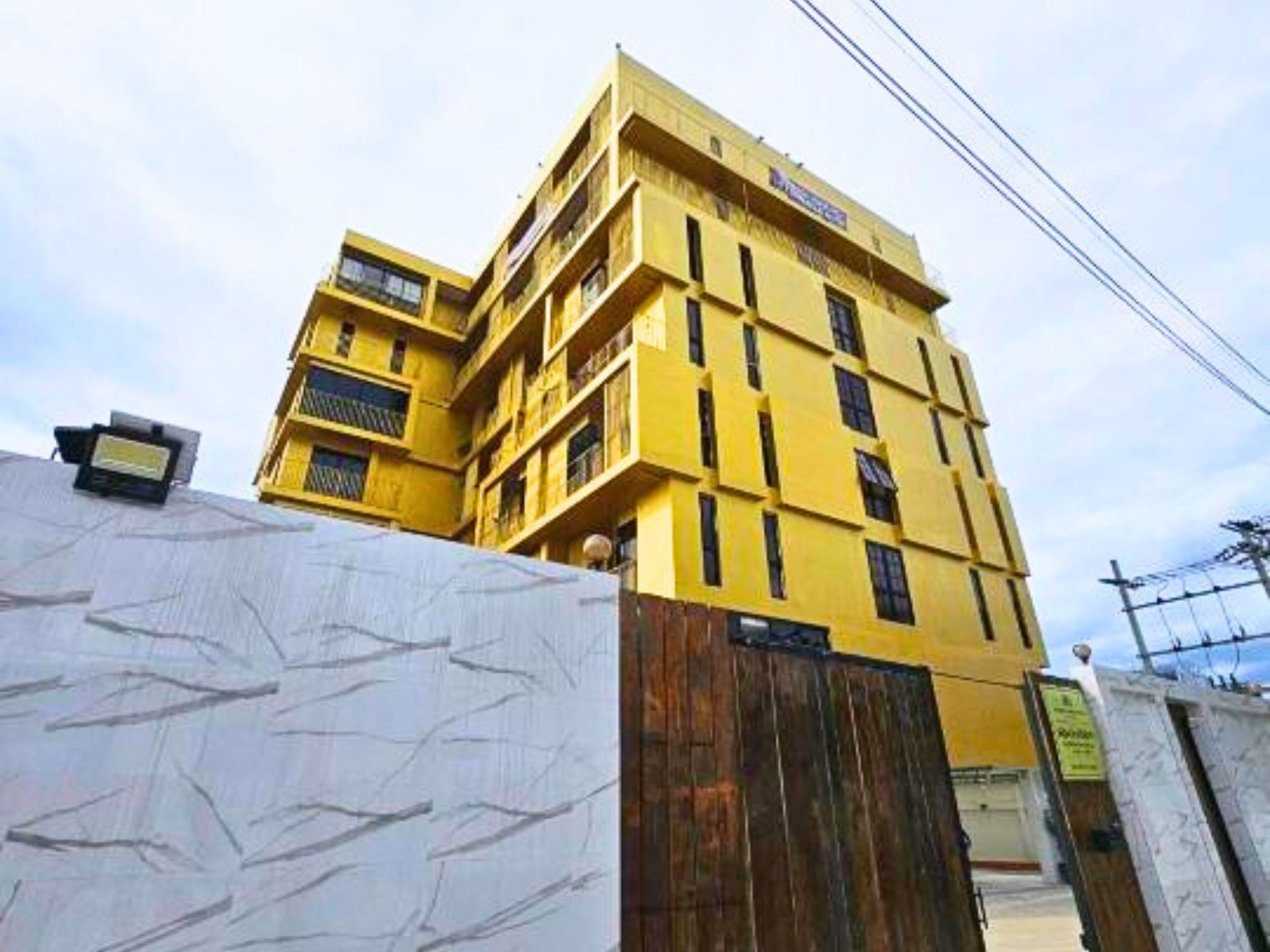Um edifício amarelo de vários andares com varandas e uma entrada protegida por grades.