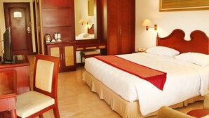 A hotel room with a large bed, a wooden desk, a chair, a mirror, and a wardrobe. - LE DIAN HOTEL & COTTAGES (Serang)