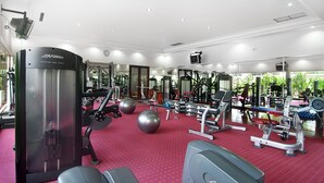 A gym with various exercise equipment, a red carpet, and a large mirror. - LE DIAN HOTEL & COTTAGES (Serang)