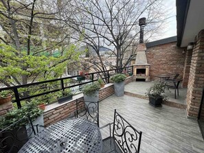 A rooftop patio with a brick fireplace, outdoor seating, and potted plants. - Hotel Cordata (Tbilisi)