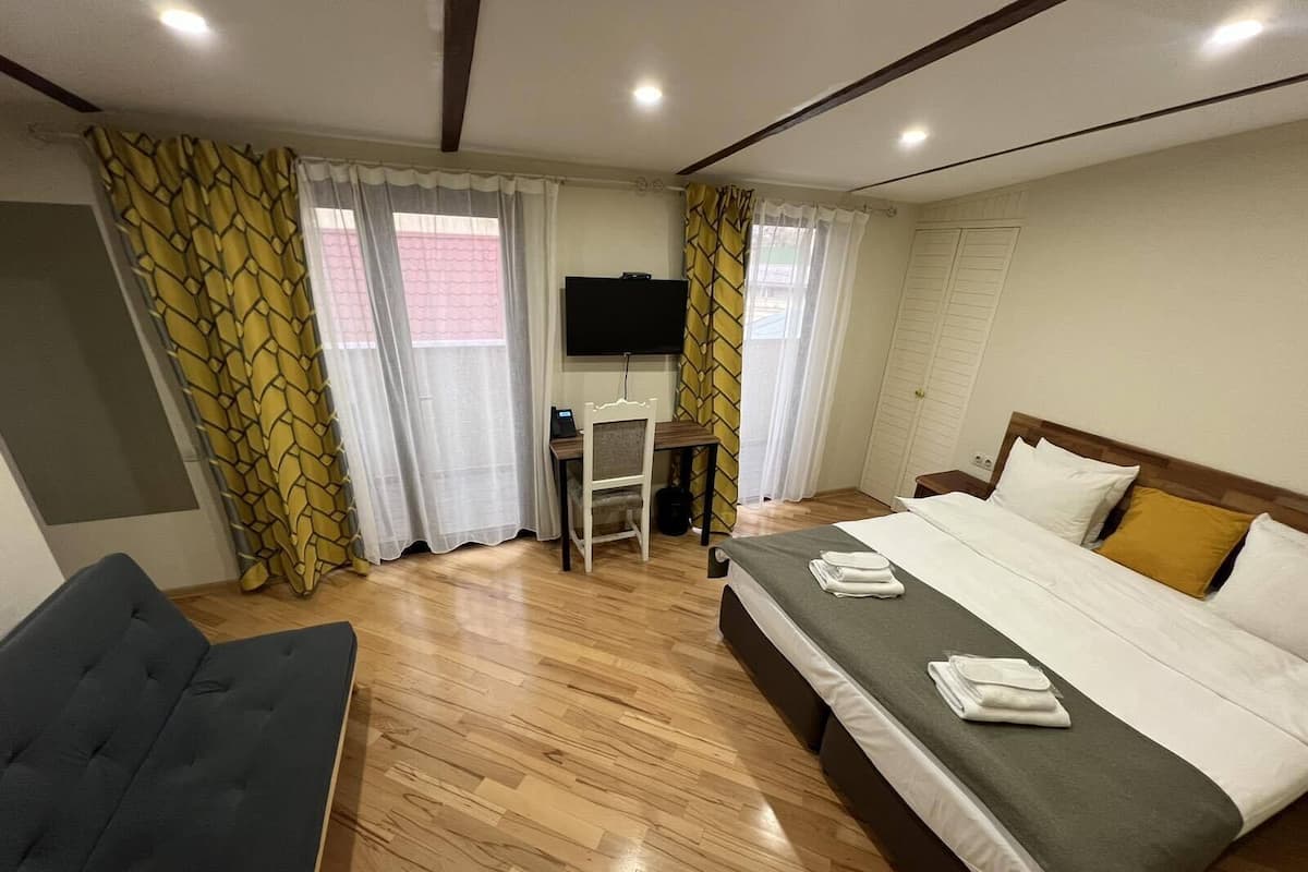 A hotel room with a bed, a desk, a chair, and a TV.