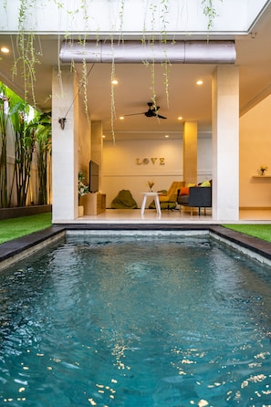 A modern indoor pool area with a seating area and a 'LOVE' sign on the wall.