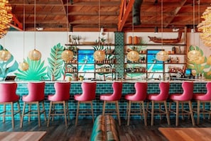 A bar area with red bar stools, a brick wall, and a wooden ceiling.