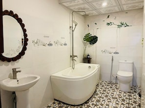 Une salle de bain avec une baignoire sur pieds, un lavabo et des toilettes.
