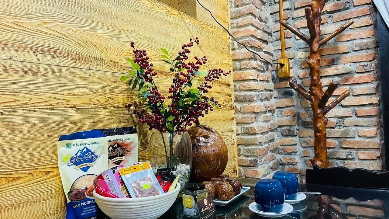 A wooden wall, a brick wall, a vase with flowers, a bowl with snacks, a tray with cups, and a wooden sculpture.