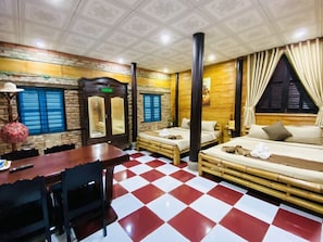 Une chambre d’hôtel avec un sol à carreaux, un lit, un canapé, une table à manger et un mur au motif texturé.