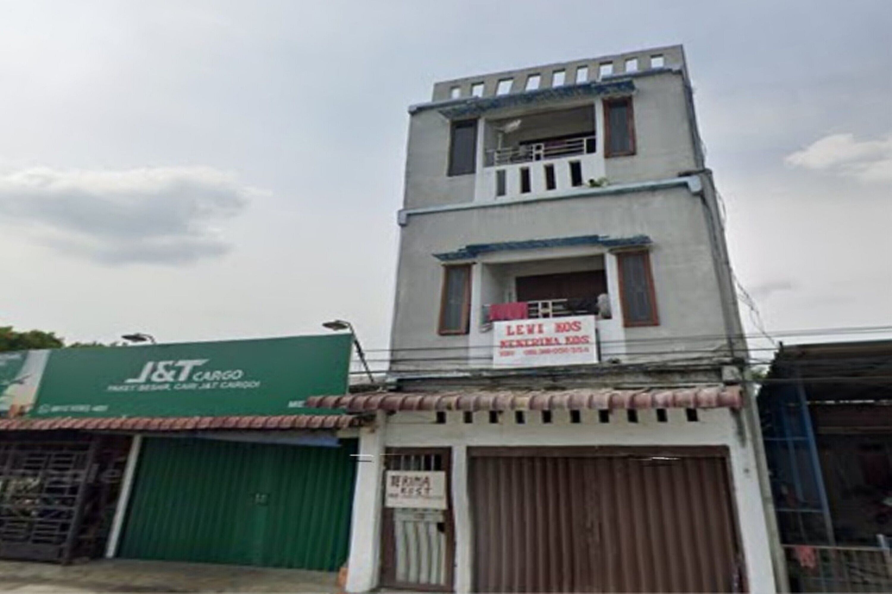 Un edifici amb un rètol verd de J&T Cargo, un rètol de Levi's i una porta metàl·lica tancada.