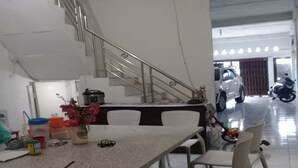 Ein Essbereich mit Tisch, Stühlen, einer Blumenvase und einer Treppe, die zu einer anderen Ebene führt.