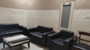 Un salon avec un canapé noir, une table basse en bois et une chaise en bois.