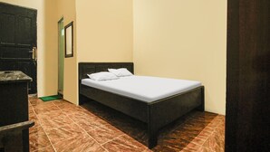 Une petite chambre à coucher, bien rangée, avec un lit simple, une commode et une porte.