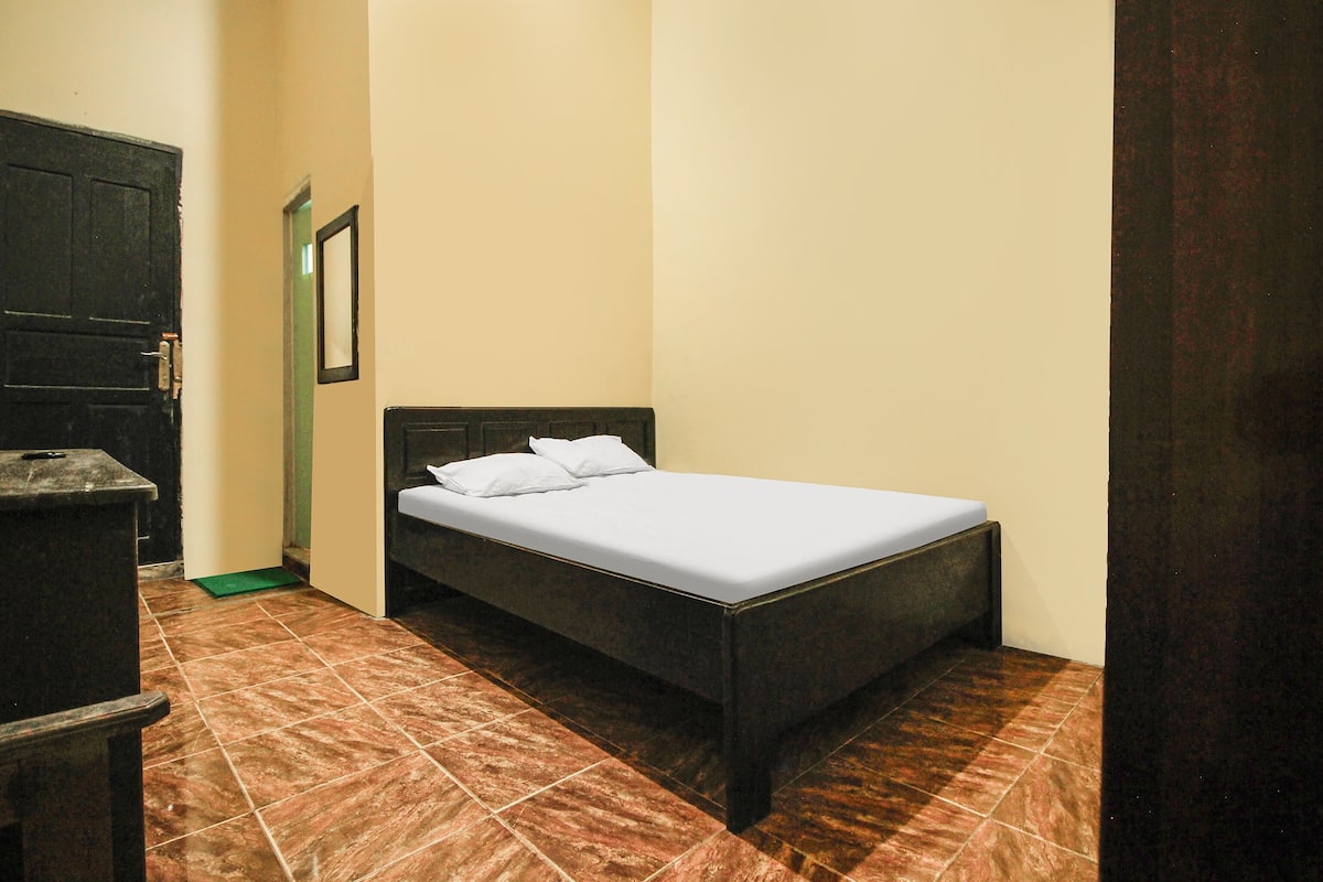 Un dormitorio pequeño y ordenado con una cama individual, un aparador y una puerta.